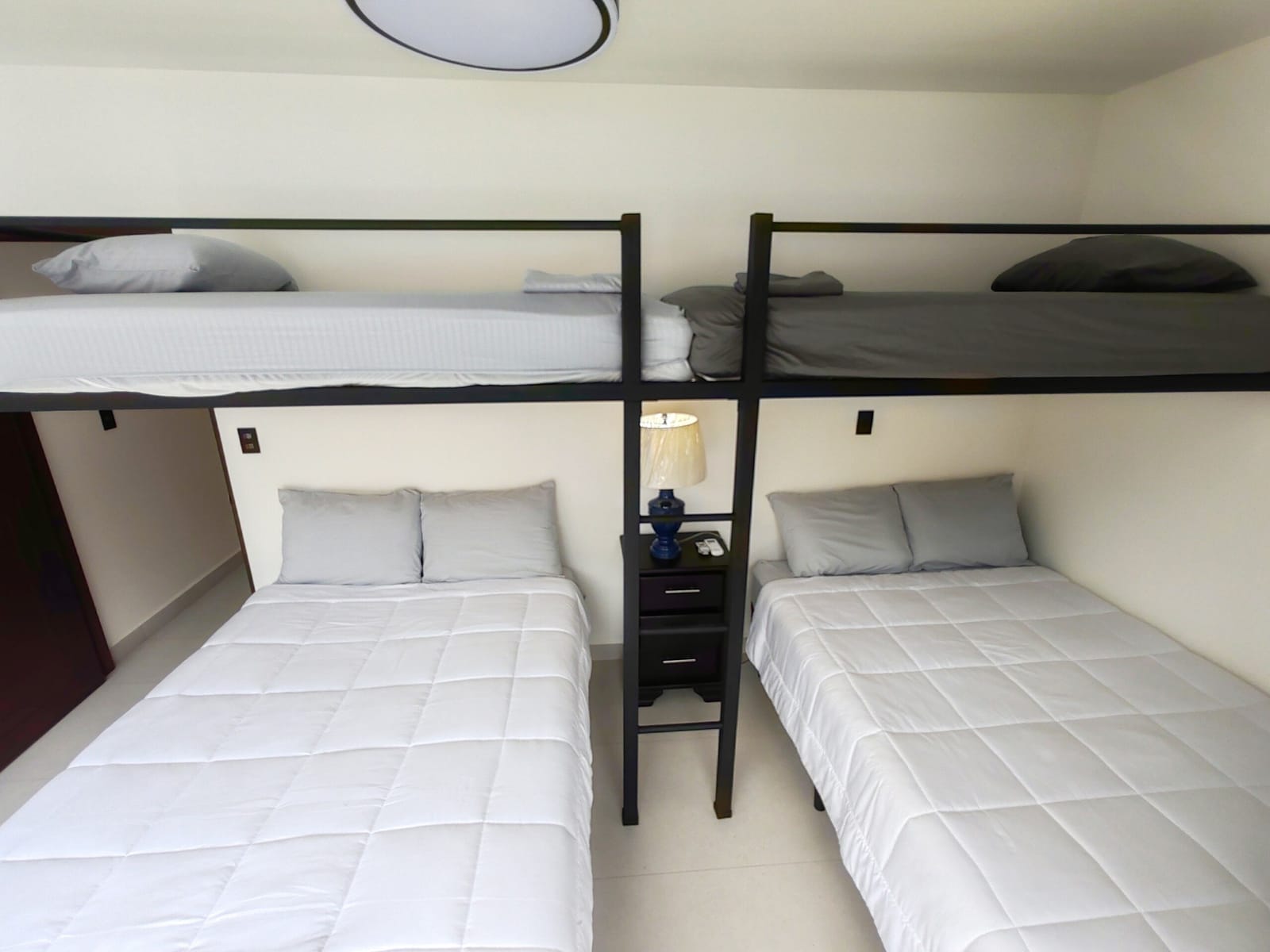 Two beds with a bunk above in the white bedroom