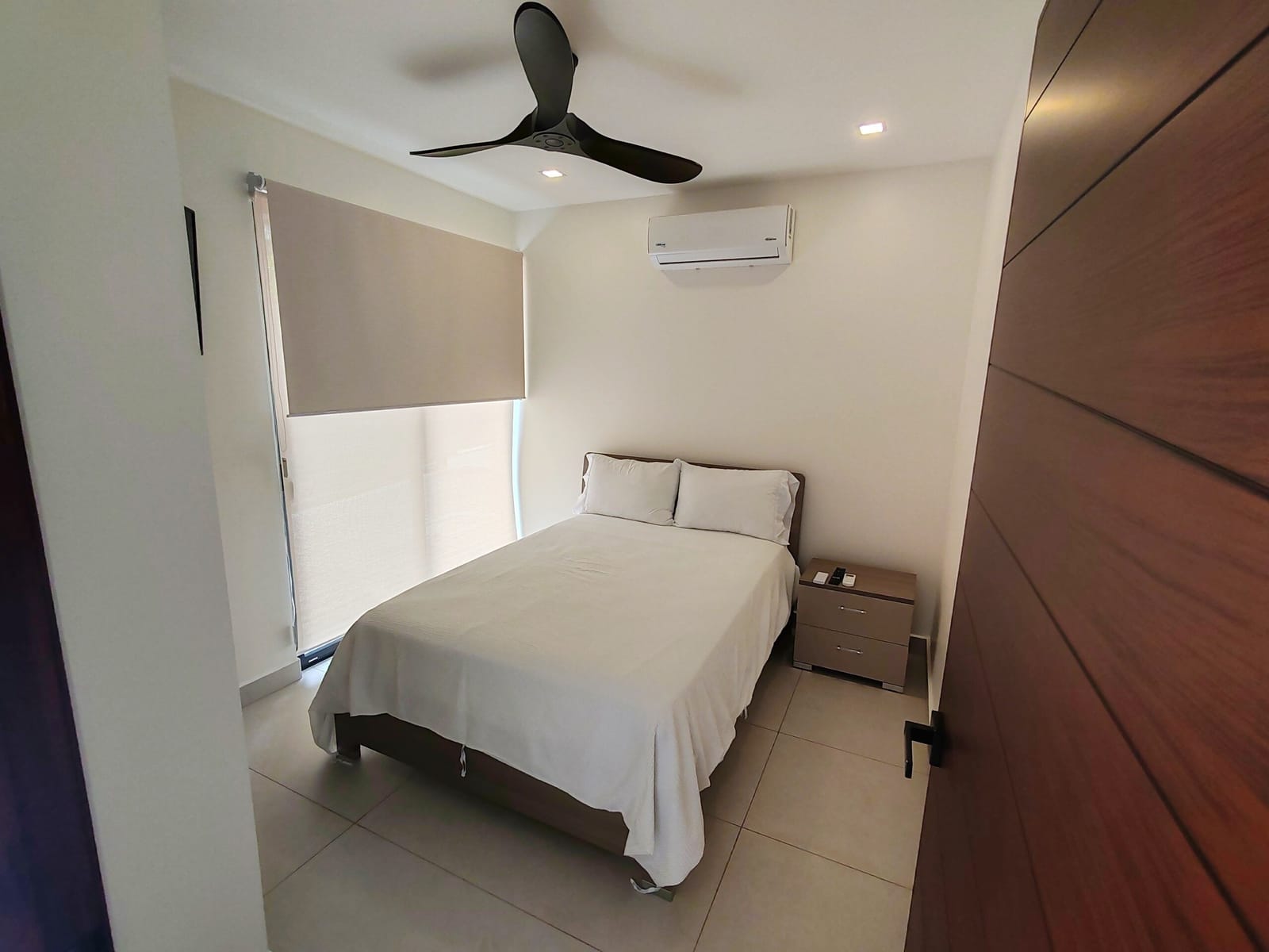 Double bed with ceiling fan and dark wood door