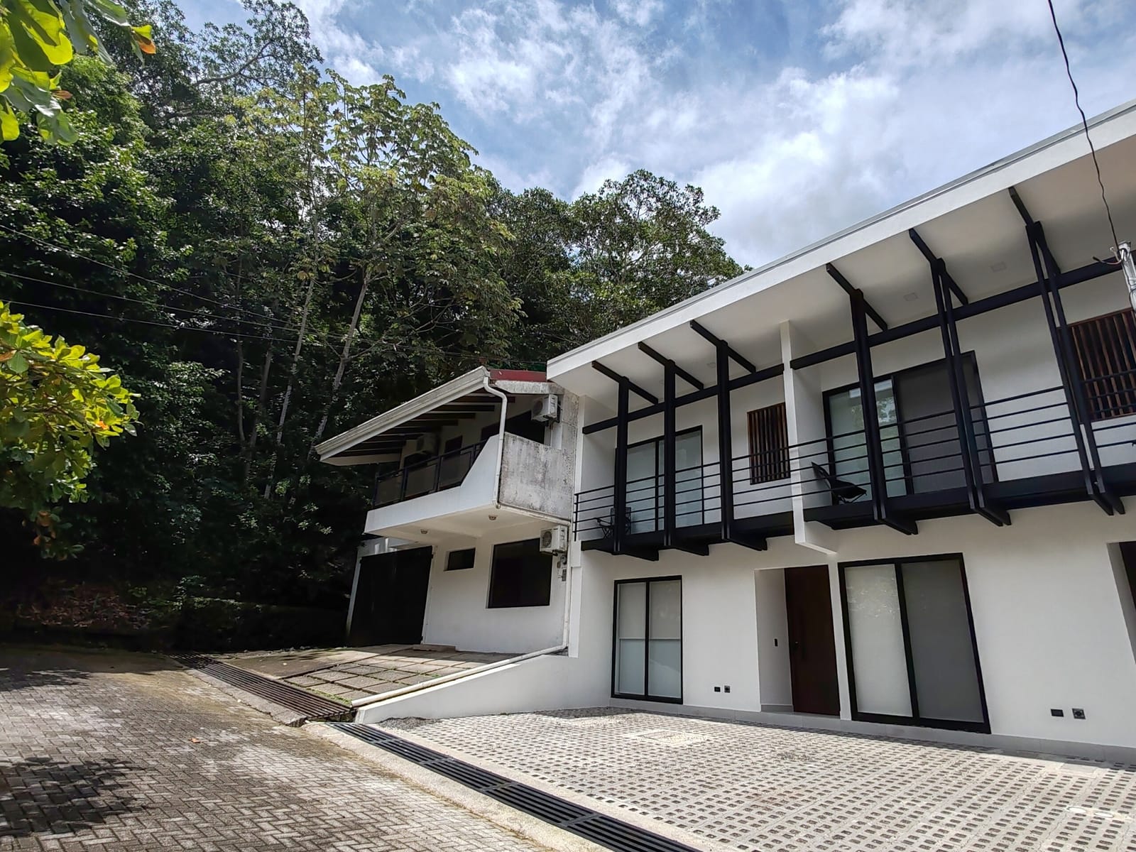 Two-story white building with black balconies and cobbled drive