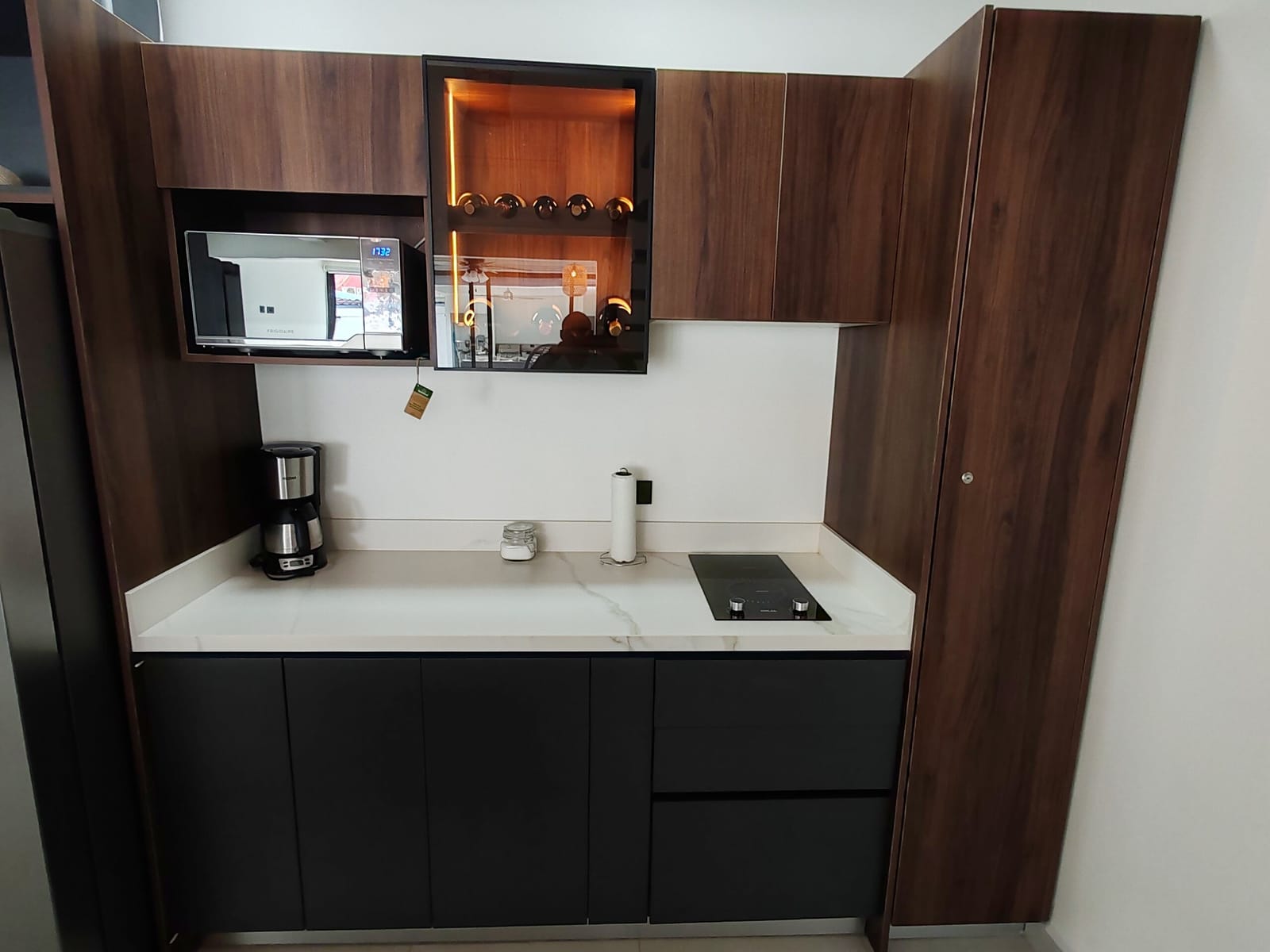 Dark wood kitchen cabinets with microwave and lit wine rack