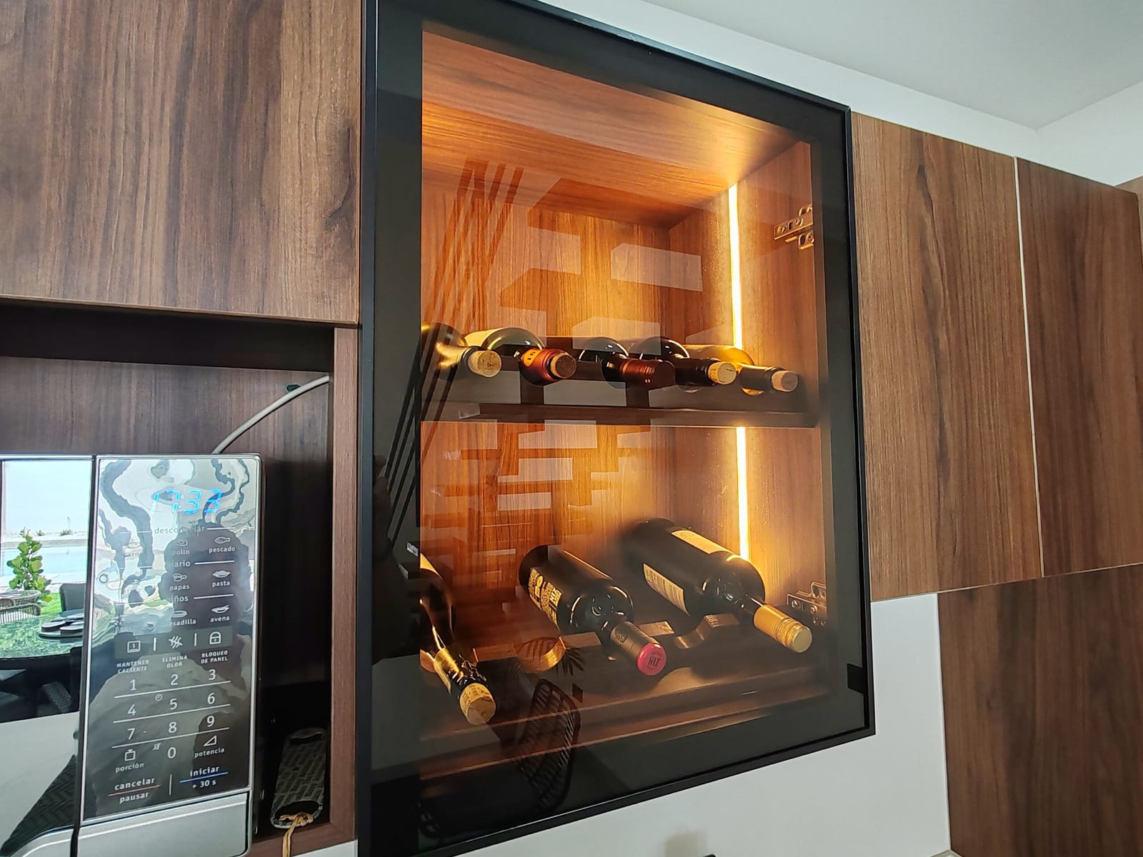 Lit wine rack set into the dark wood cabinets