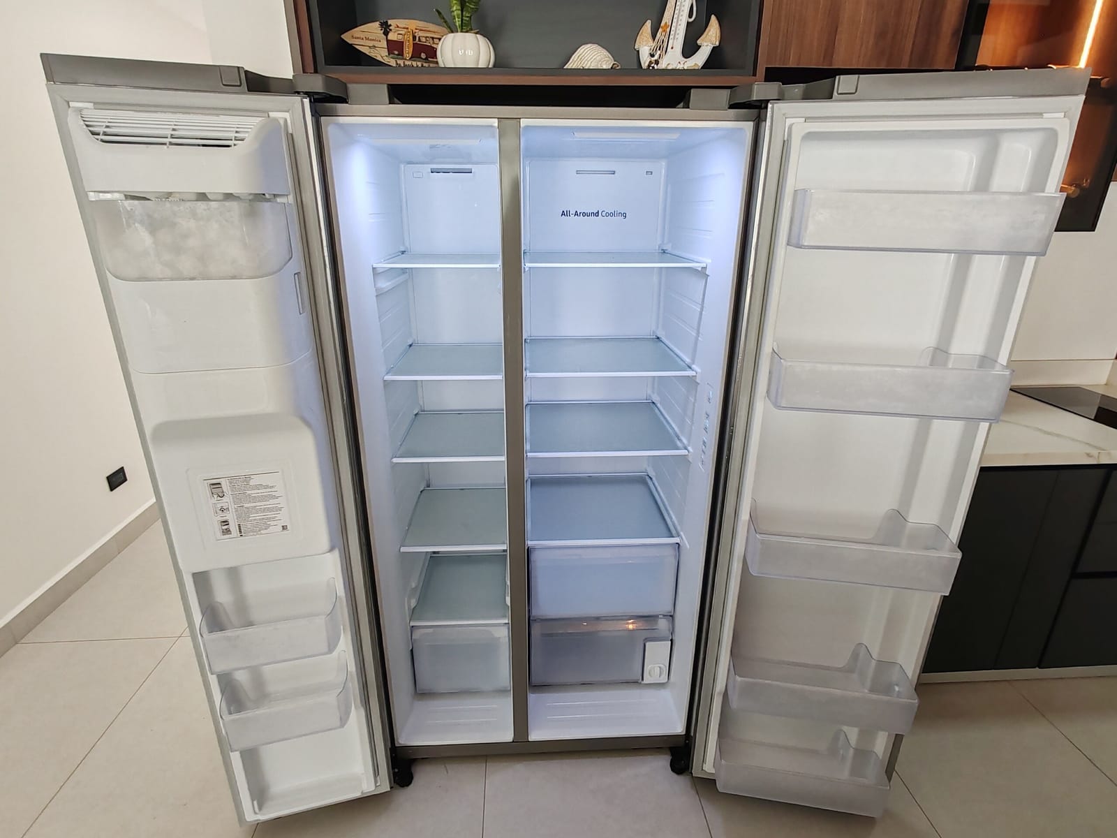 Side-by-side refrigerator standing open with its empty shelves
