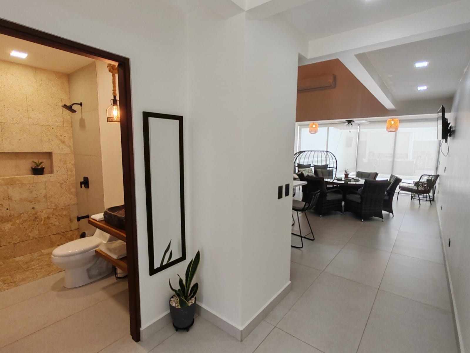 Bathroom with stone shower, tall mirror and plant