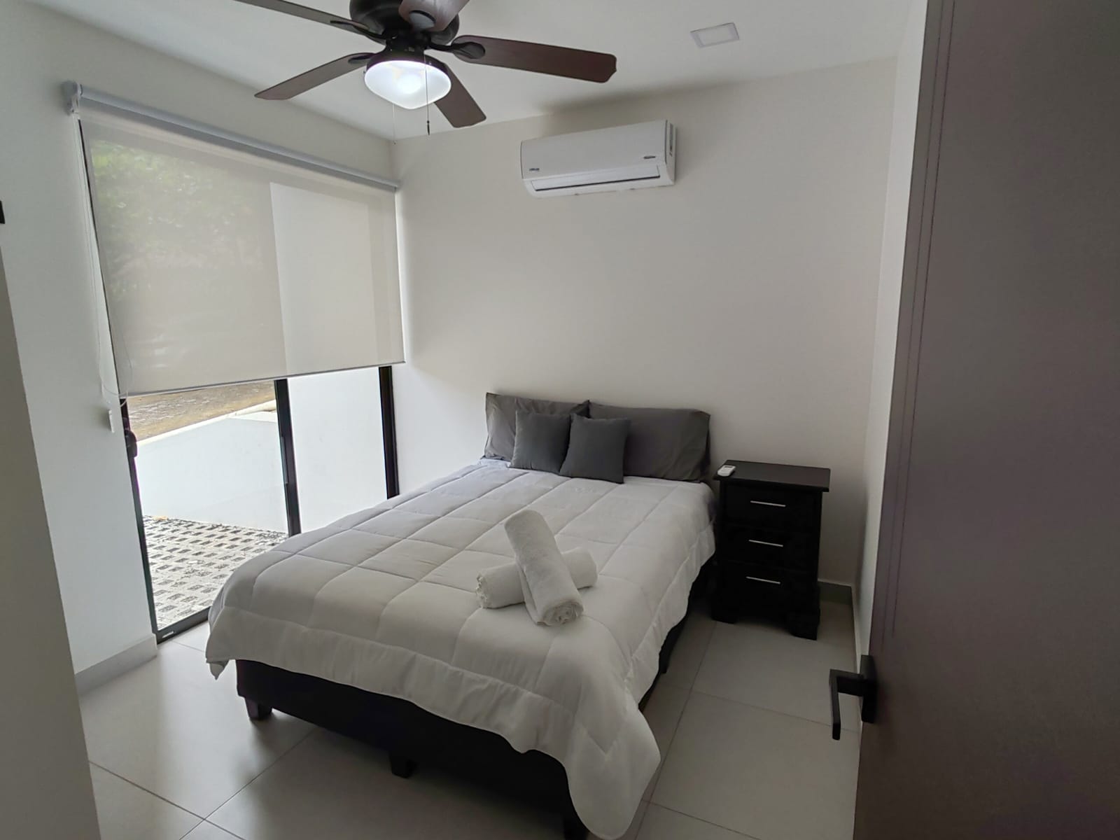 Bedroom with double bed and dark nightstand under a fan