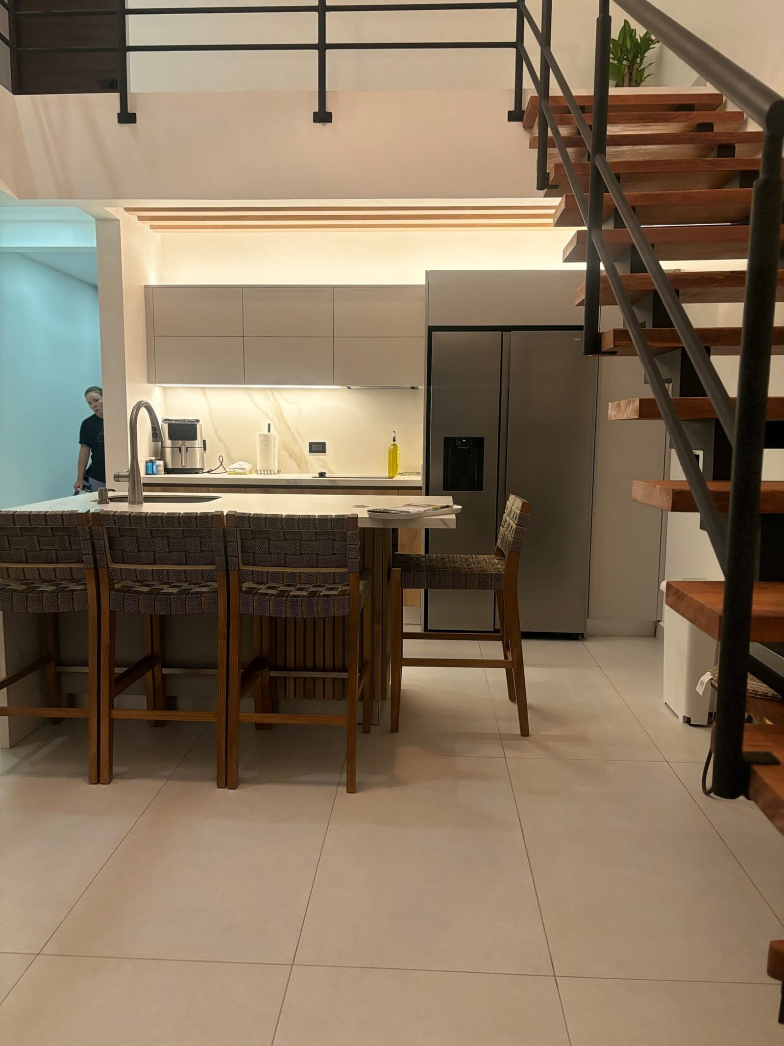 Kitchen island with woven stools under the floating stair