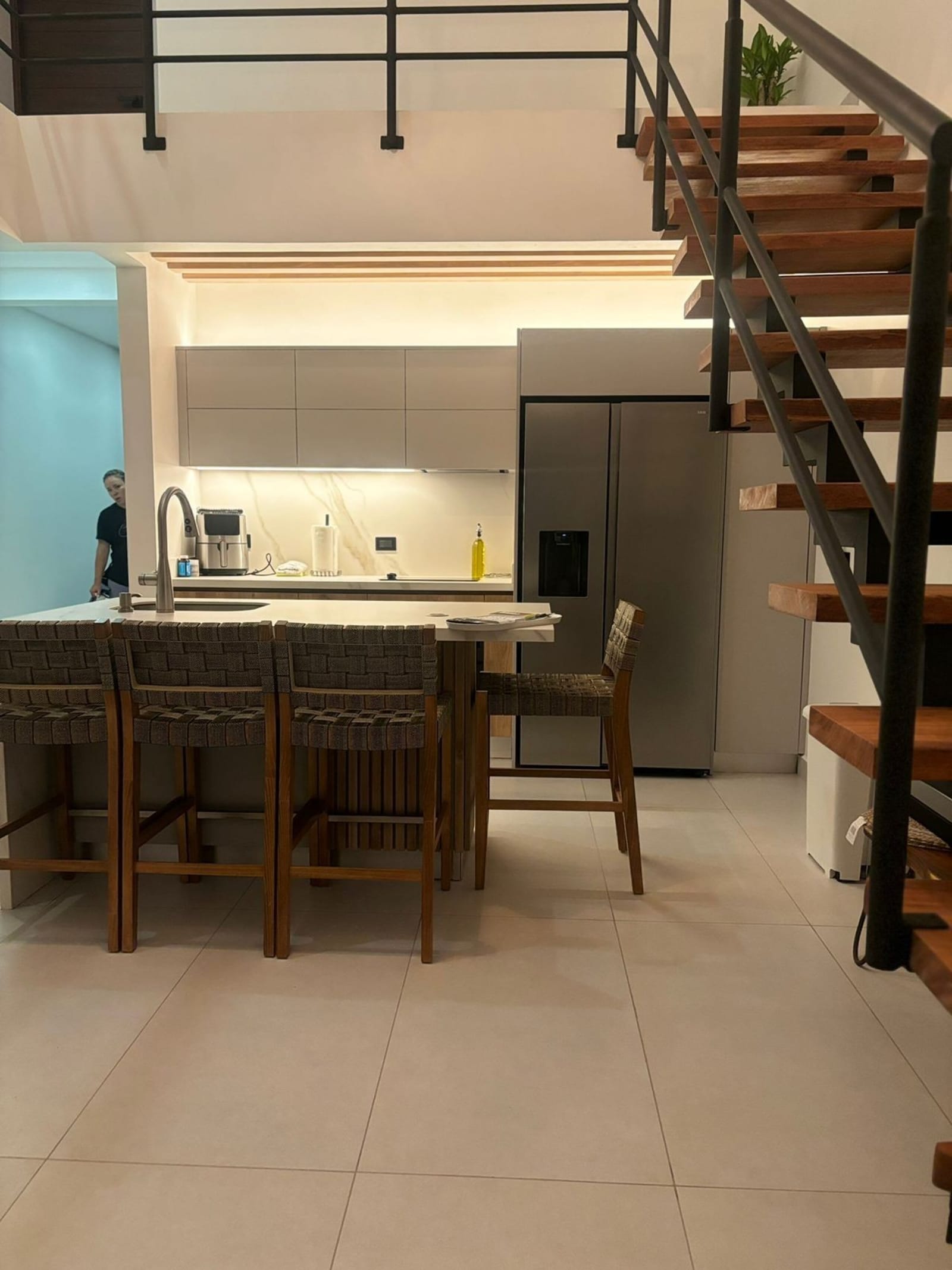 Kitchen island with stools beneath the floating wooden stair