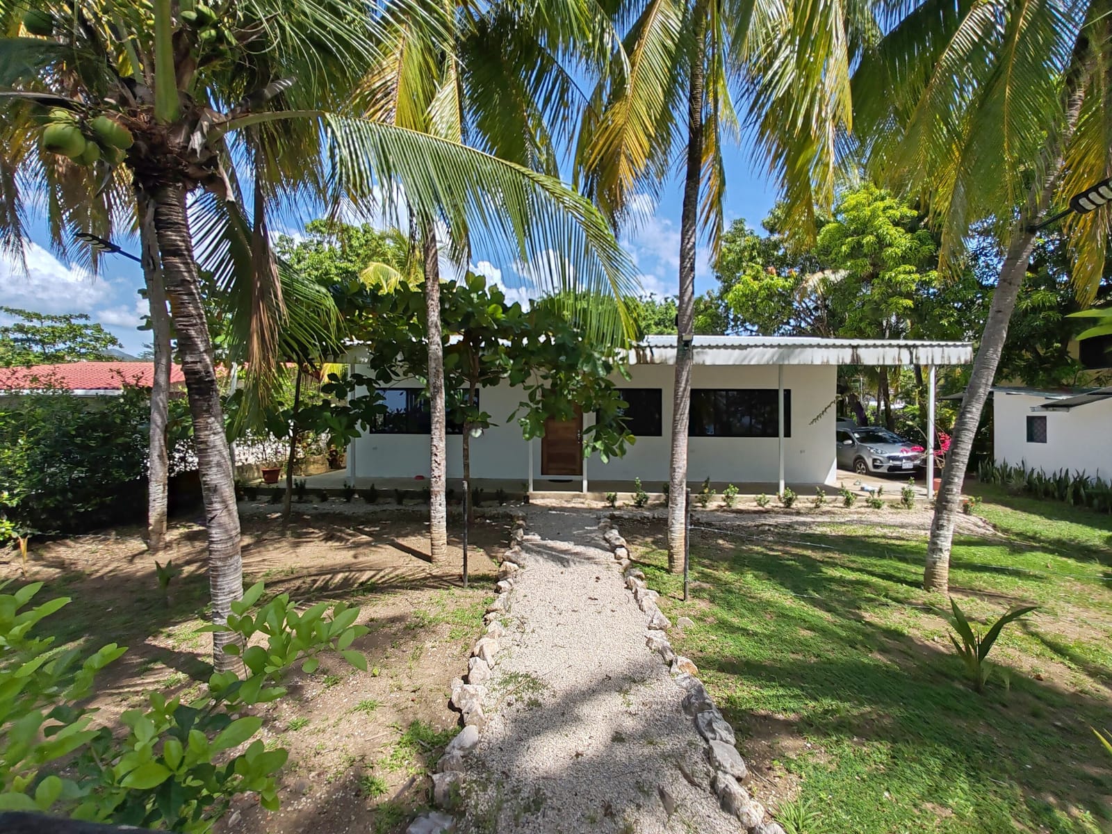 White beach house under coconut palms with a stone path