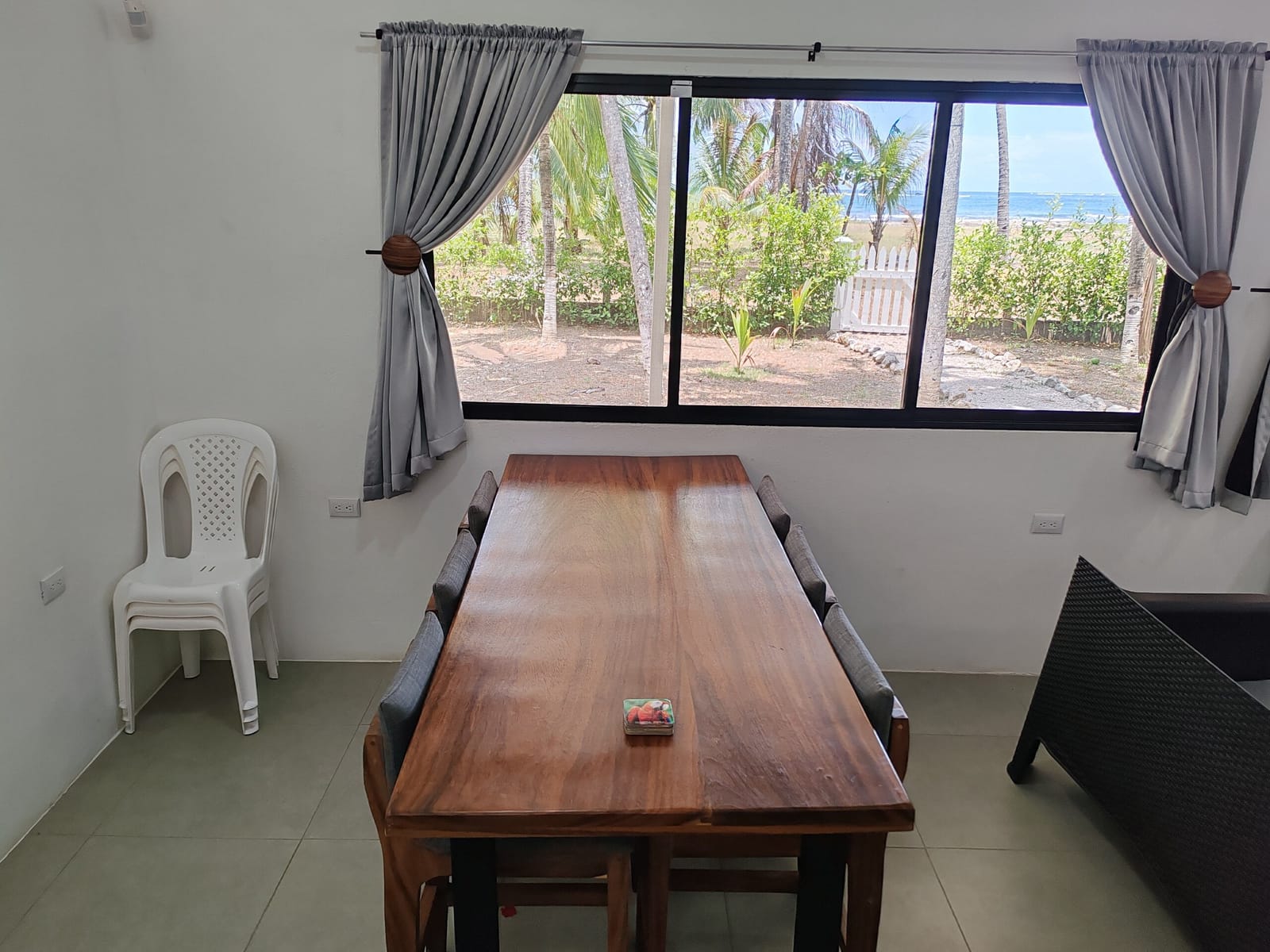 Wooden dining table with white chairs and curtains