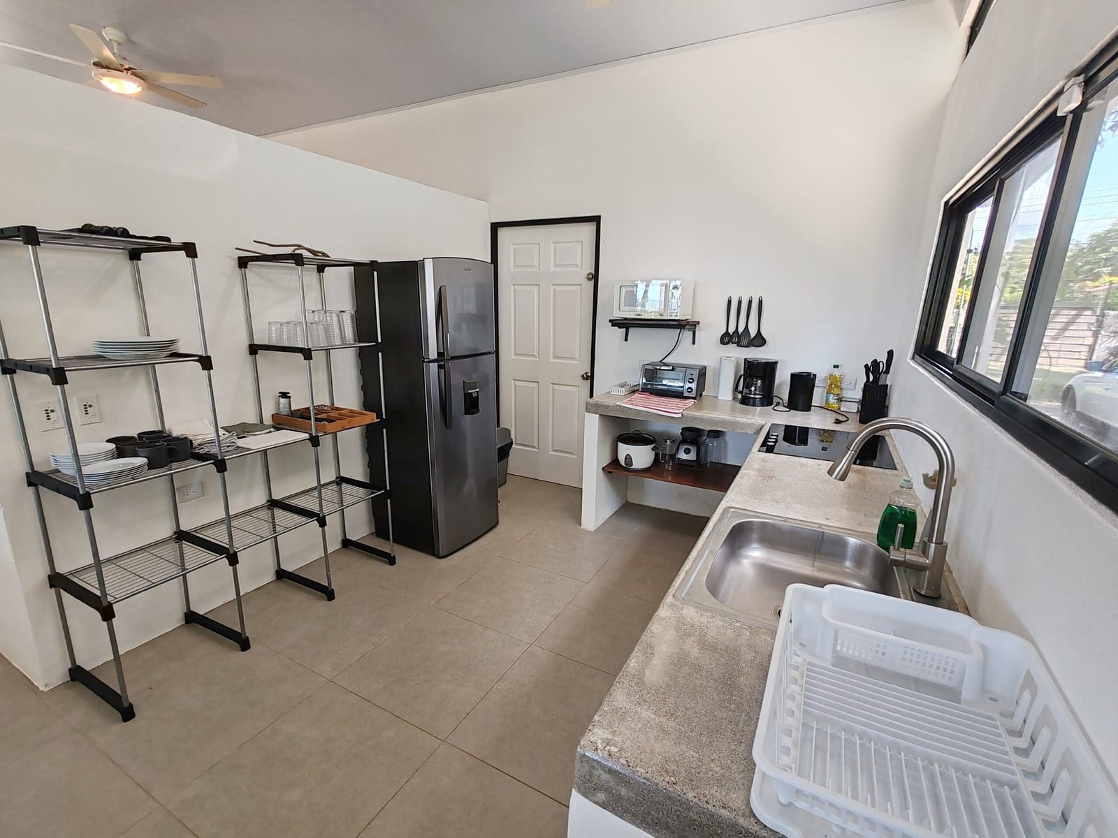 Kitchen with metal shelving, refrigerator and sink with dish rack