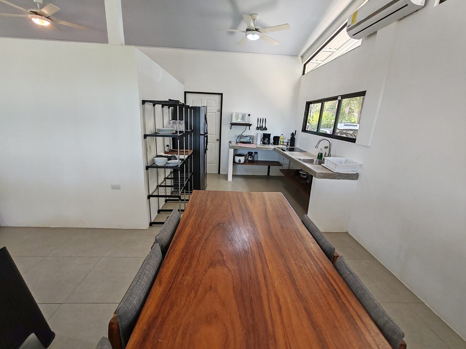 Long dining table with the kitchen shelves and door behind