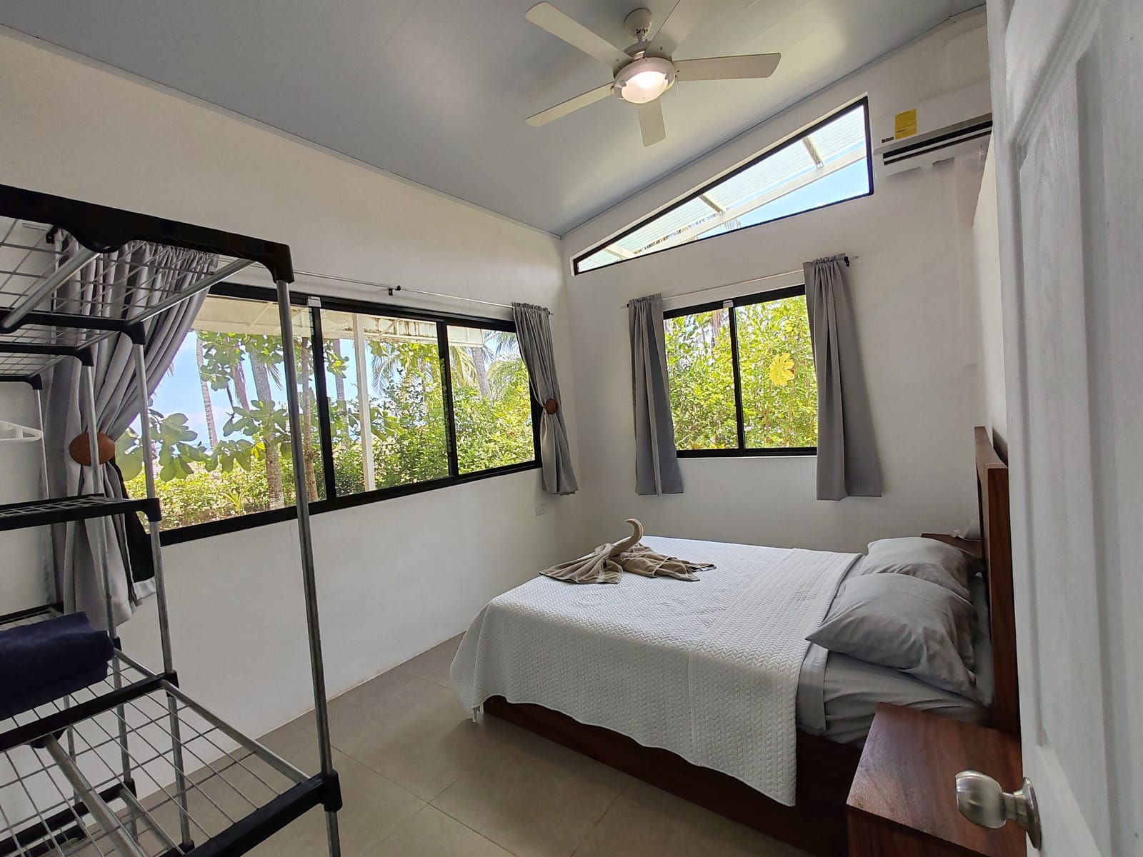 Bedroom with bed, ceiling fan and windows to the palms