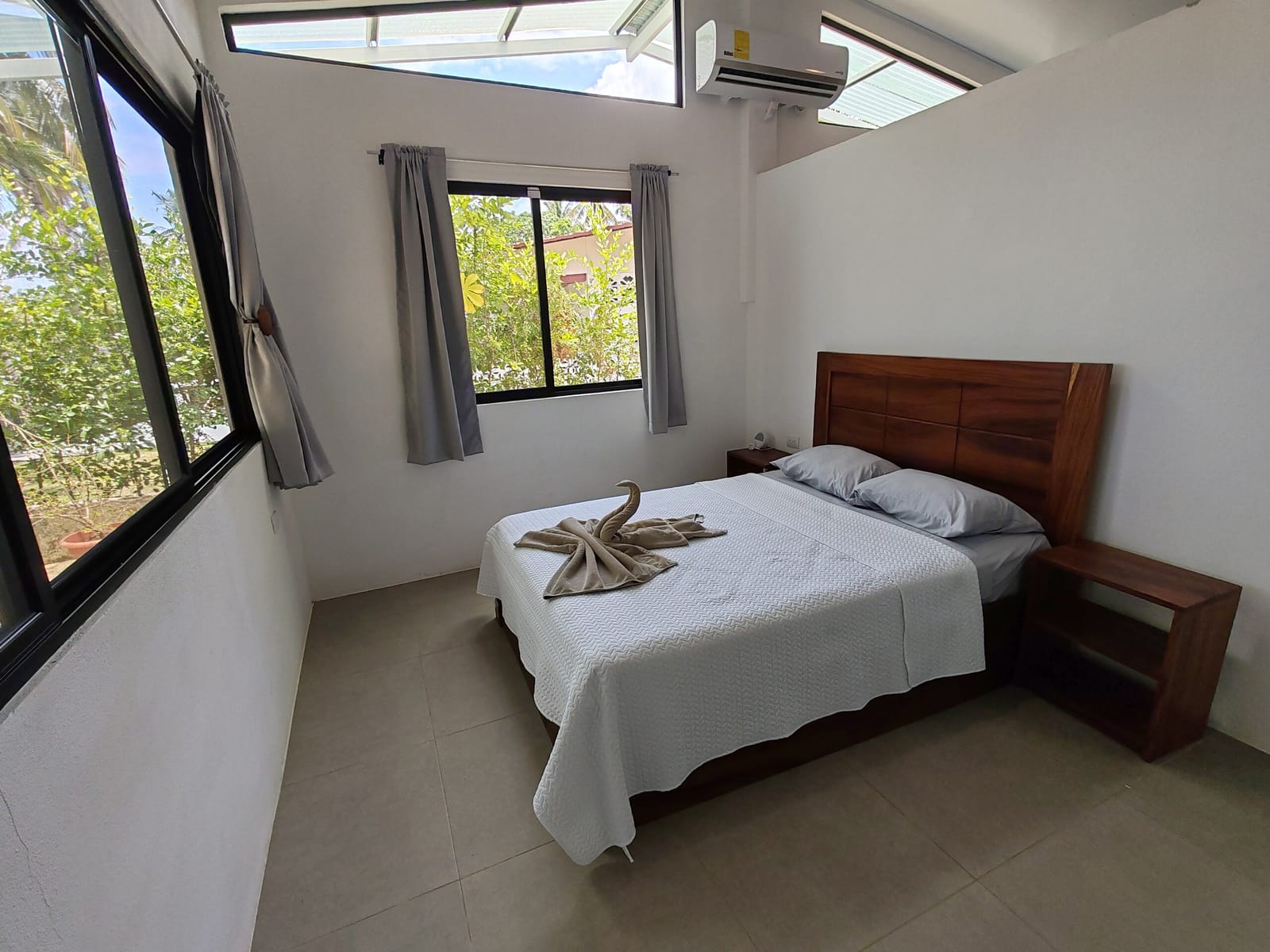 Double bed with towel decoration and windows on two sides