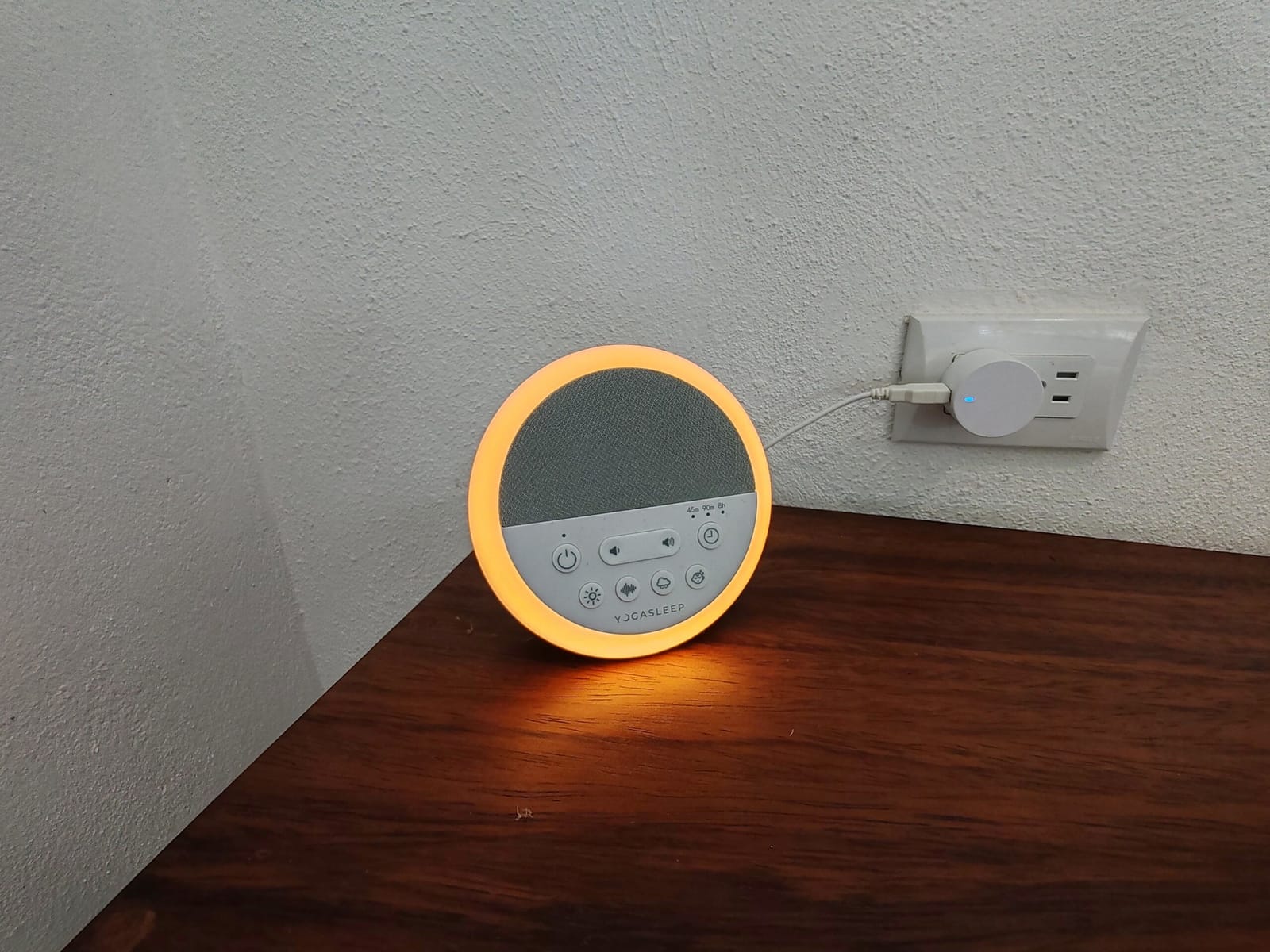 Round bedside lamp glowing on a wooden side table