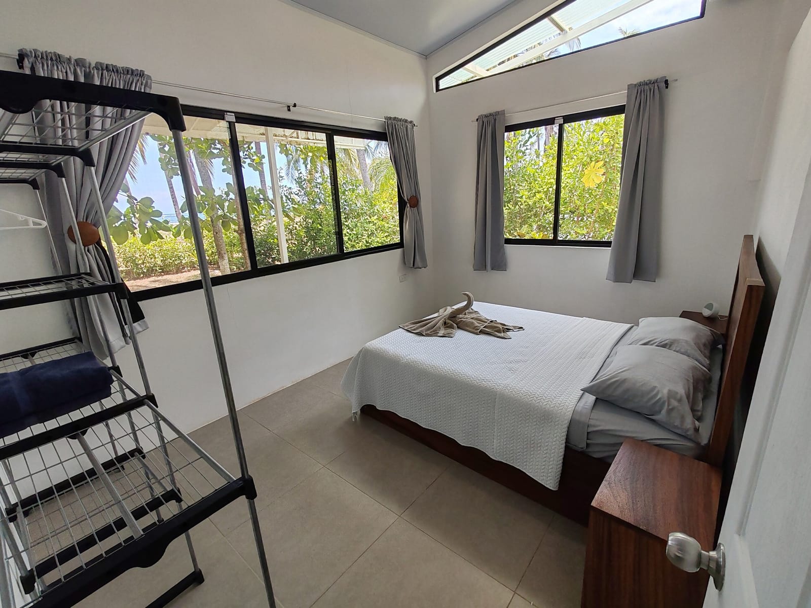 Bedroom with bed, curtains and a metal clothes rack