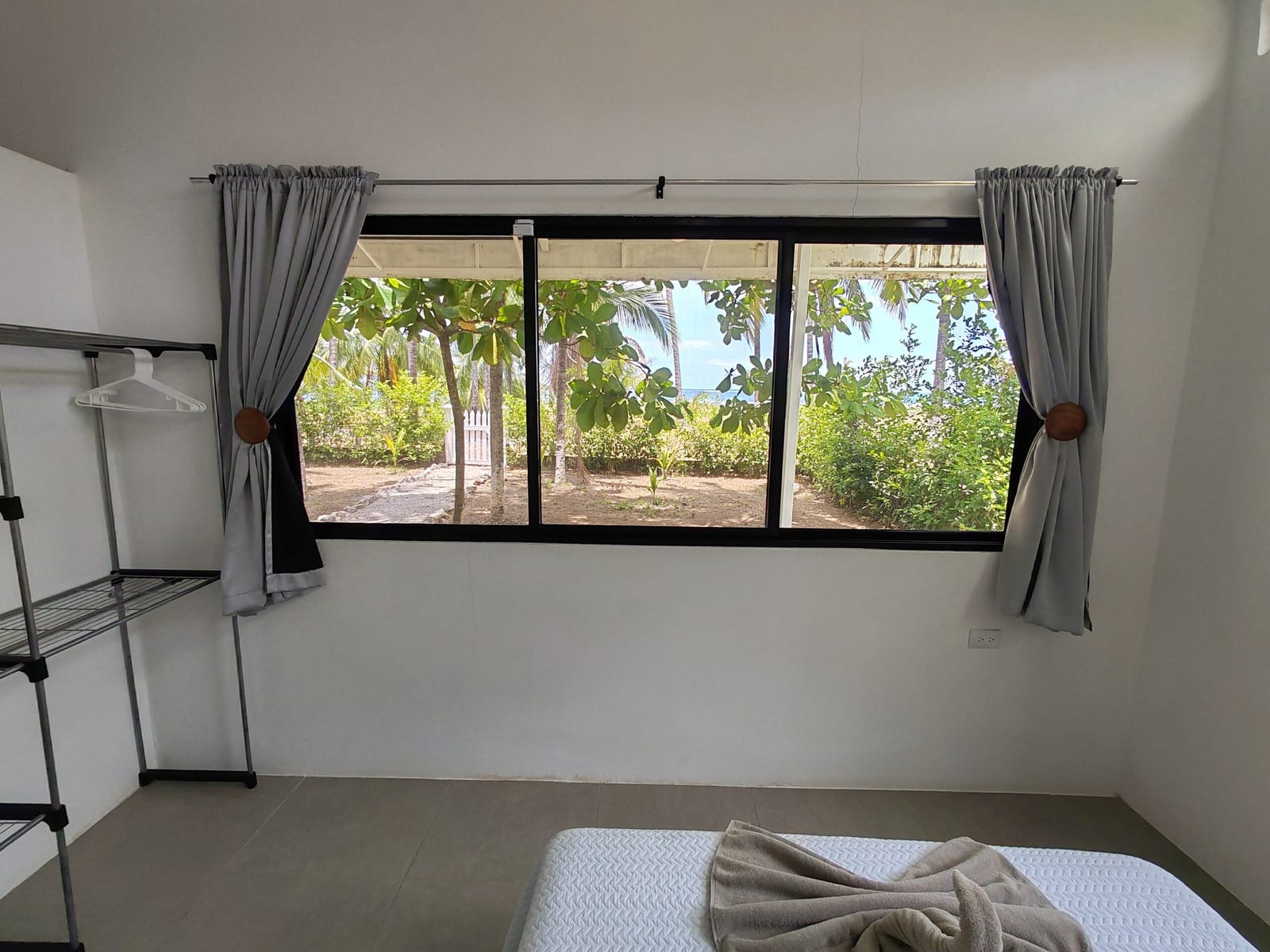 Bedroom with wooden bed frame and view of the beach trees