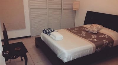 A double bed made up with folded towels, in a small bedroom with white closet doors